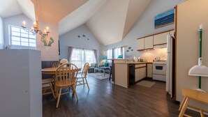 A modern kitchen with wooden cabinets, a dining area with a wooden table and chairs, and a kitchen island. - Mandalay Shores Resort (Oxnard)