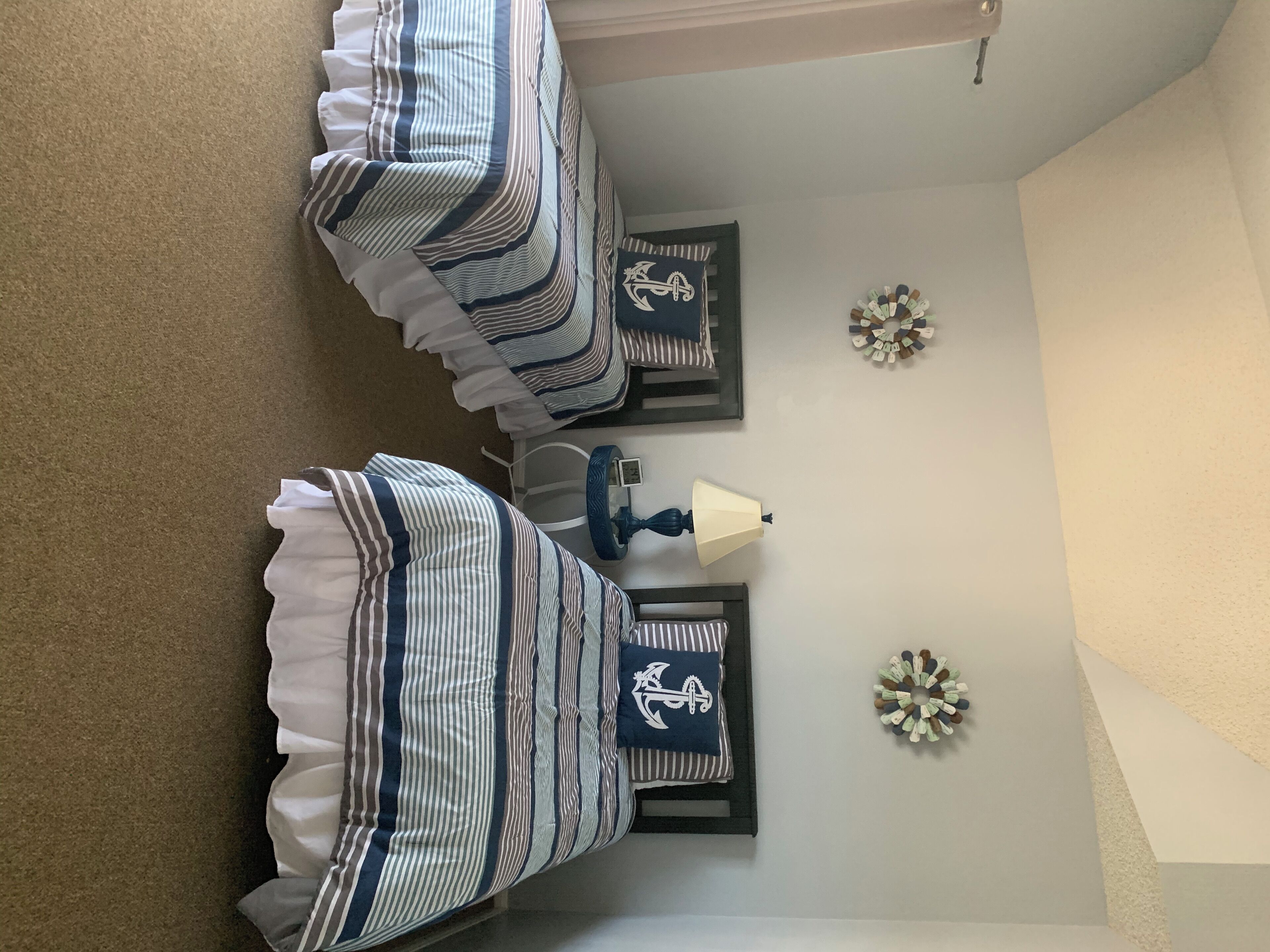 Un dormitorio con dos camas, una mesita de noche, una lámpara y decoración en la pared.