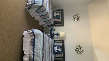 Un dormitorio con dos camas, una mesita de noche, una lámpara y decoración en la pared.