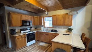 Una cocina con armarios de madera, una estufa, un microondas y un fregadero.