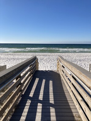 A wooden boardwalk leading to a sandy beach with a clear blue sky. - Updated Coastal Condo • Steps to Beach • Pool • King + Bunks • Ground Floor (Fort Walton Beach)
