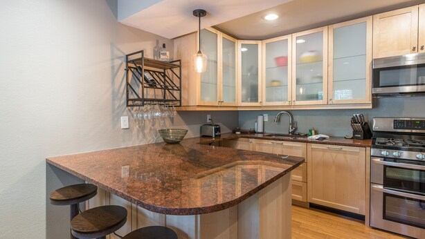 A kitchen with granite countertops, wooden cabinets, stainless steel appliances, and bar stools. - On Free City Bus Route! Hot Tub! Fireplace! (Steamboat Springs)