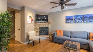 A living room with a fireplace, a sofa, a coffee table, and a ceiling fan. - On Free City Bus Route! Hot Tub! Fireplace! (Steamboat Springs)