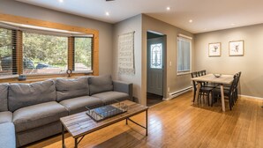 A living room with a gray sofa, wooden coffee table, and a dining area with a table and chairs. - On Free City Bus Route! Hot Tub! Fireplace! (Steamboat Springs)