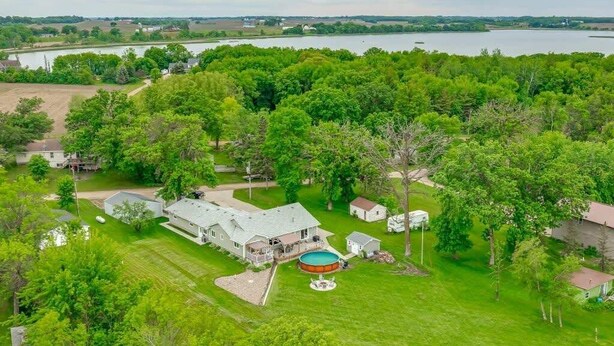 A large house with a swimming pool, surrounded by lush greenery and a lake. - Lake Front Home with Pool and Stunning Views (Annandale)