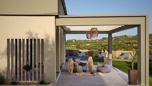Terrassa exterior moderna amb una pèrgola, zona de seients i vistes a una collada.