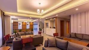 A modern hotel lobby with sofas, a reception desk, and a staircase leading to an upper floor. - Business Hotel Antalya (Antalya)