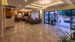 A hotel lobby with a reception desk, seating area, and large glass doors leading to the street. - Business Hotel Antalya (Antalya)