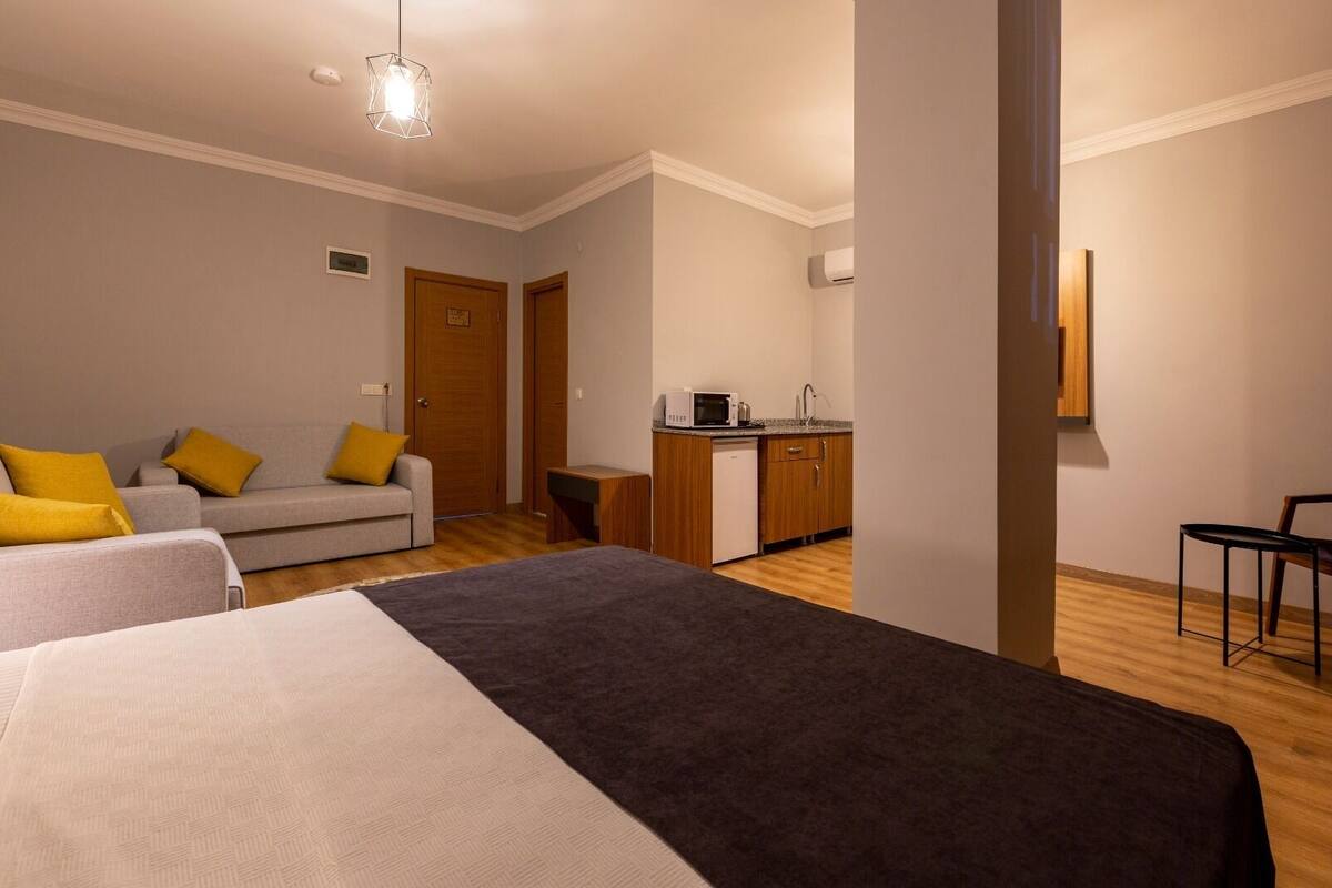 Ein Hotelzimmer mit Bett, einer Couch, einer kleinen Küchenzeile und einem Esstisch.