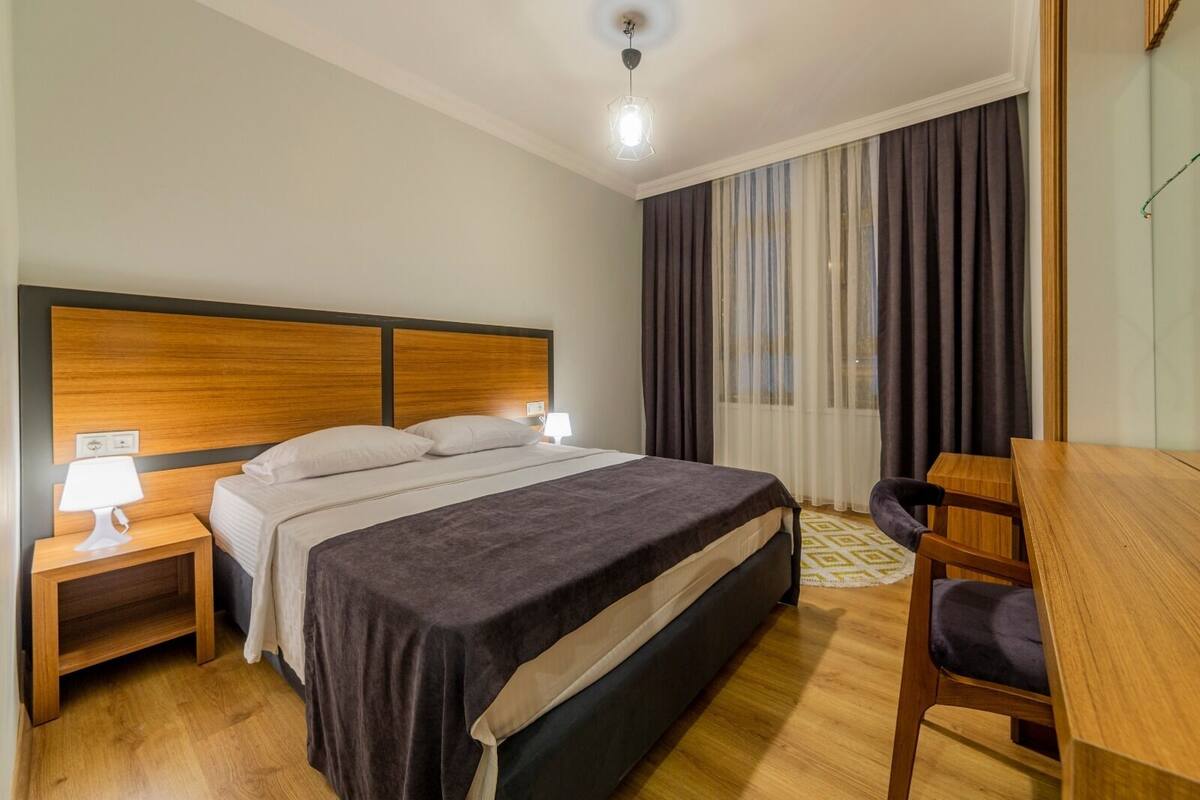 Ein Hotelzimmer mit Bett, Nachttisch, Lampe und Schreibtisch mit Stuhl.