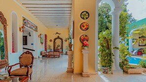 A spacious lobby with a tiled floor, wooden furniture, and a pool area visible through an open archway. - Hotel Santa María Mérida (Mérida)
