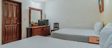 Une chambre d’hôtel avec deux lits, une commode en bois, un téléviseur et un ventilateur de plafond.