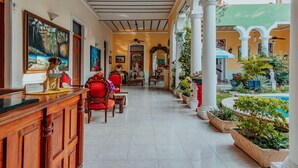 A hotel lobby with a reception desk, seating area, and a view of the outdoor garden. - Hotel Santa María Mérida (Mérida)