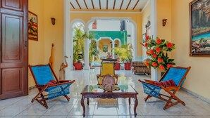 A spacious lobby with two wooden chairs, a glass coffee table, and a large painting on the wall. - Hotel Santa María Mérida (Mérida)