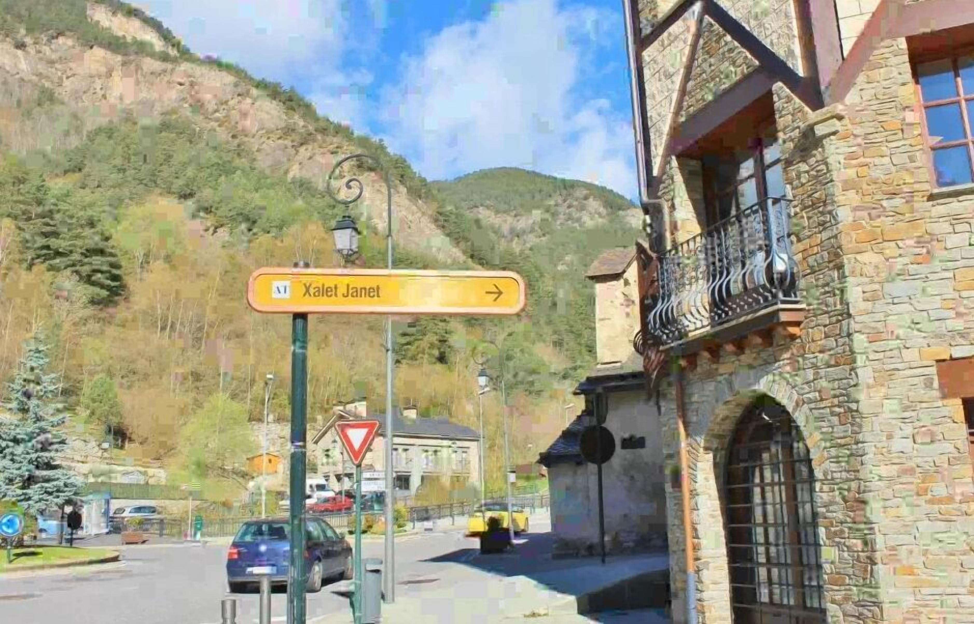 A street view with a sign for 'Kalet Janel' and a stone building with a balcony.