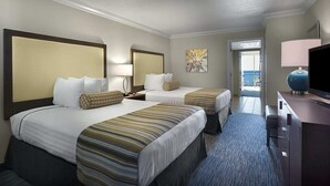 Ein Hotelzimmer mit zwei Betten, einem Fernseher, einem Schreibtisch und einem Fenster.