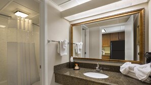 Ein Badezimmer mit Granitplatte, einem weißen Waschbecken, einem großen Spiegel und einer Duschvorhang.