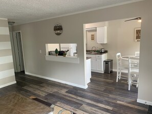 A modern kitchen with white cabinets, a built-in island, and a dining area with white chairs. - Adventure Acres- Suite C3 (Holly)