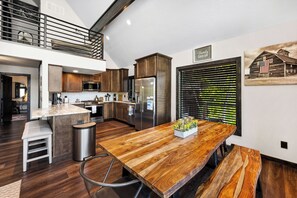 A modern kitchen with a central island, stainless steel appliances, and a rustic wooden dining table. - Hayden Lakefront Cabin w/ Private Dock & Stunning Views for Families (Hayden)