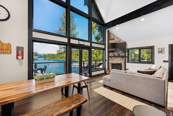 A spacious living area with a large window overlooking a pool, a fireplace, and a sofa.