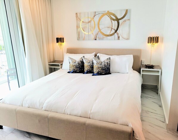 A large bed with white bedding, two bedside tables with lamps, and a wall art piece above the bed. - LUX! Jr ONE BD AT ESJ TOWERS, VIEW,LOCATION,SO CHIC! (Carolina)