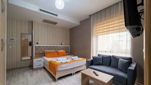 Une chambre d’hôtel moderne équipée d’un lit, d’un canapé, d’une table basse et d’un téléviseur.