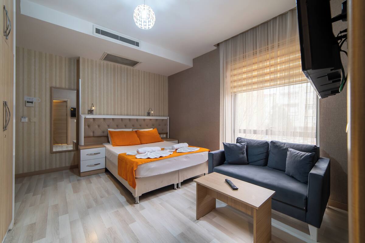 Et moderne hotelværelse med seng, sofa, sofabord og fjernsyn.