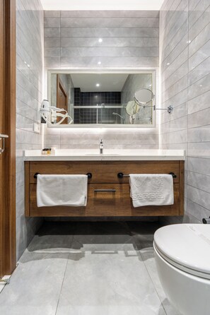 A modern bathroom with a white sink, wooden vanity, two towels, a mirror, and a toilet. - Mardy Hotel (Istanbul)