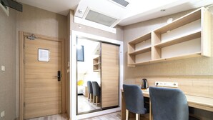 Une chambre moderne avec une porte en bois, un bureau avec une chaise et un placard avec une porte miroir.