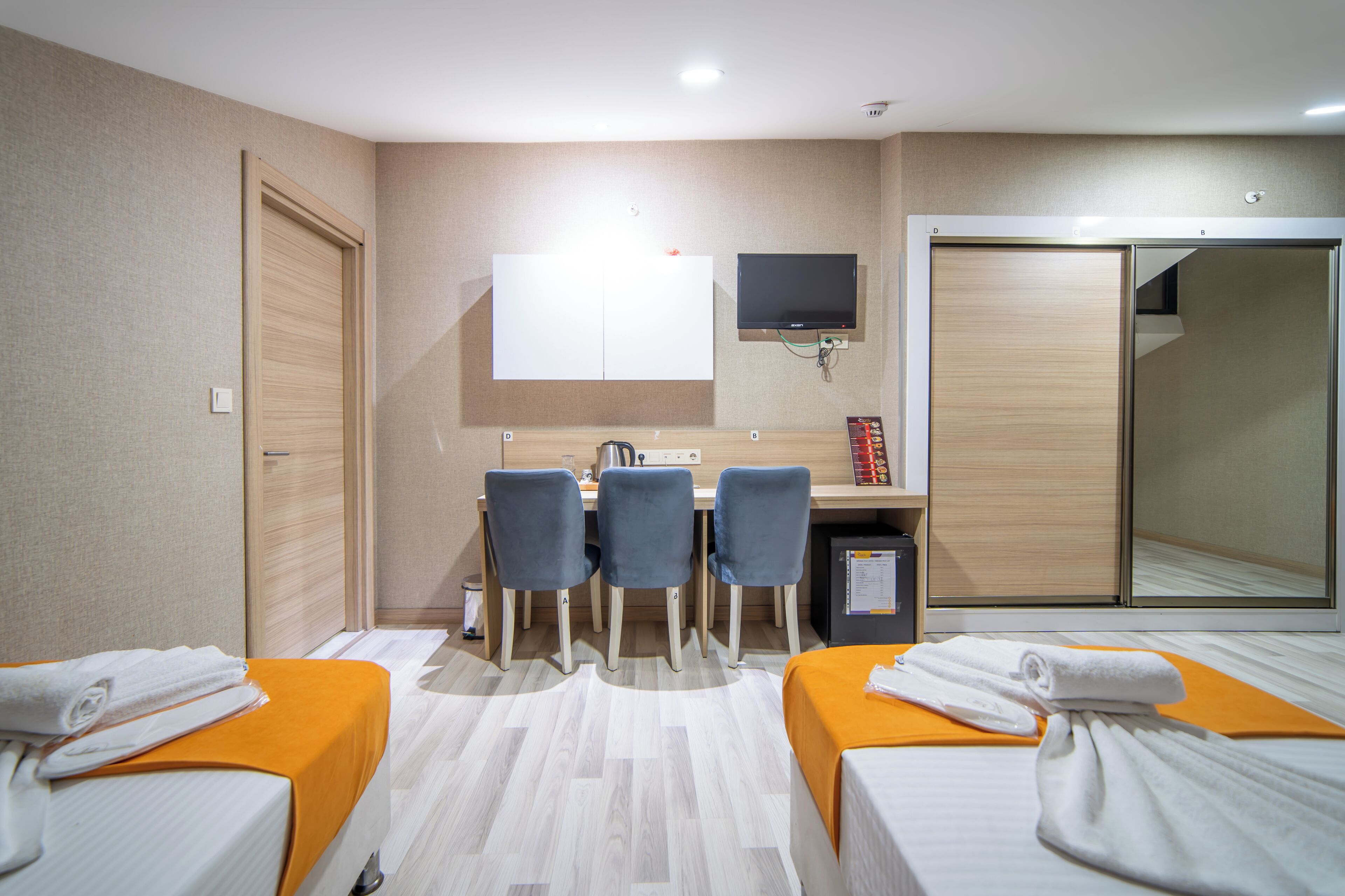 Hotellihuone, jossa on kaksi sänkyä, työpöytä tuoleineen, televisio ja peili.