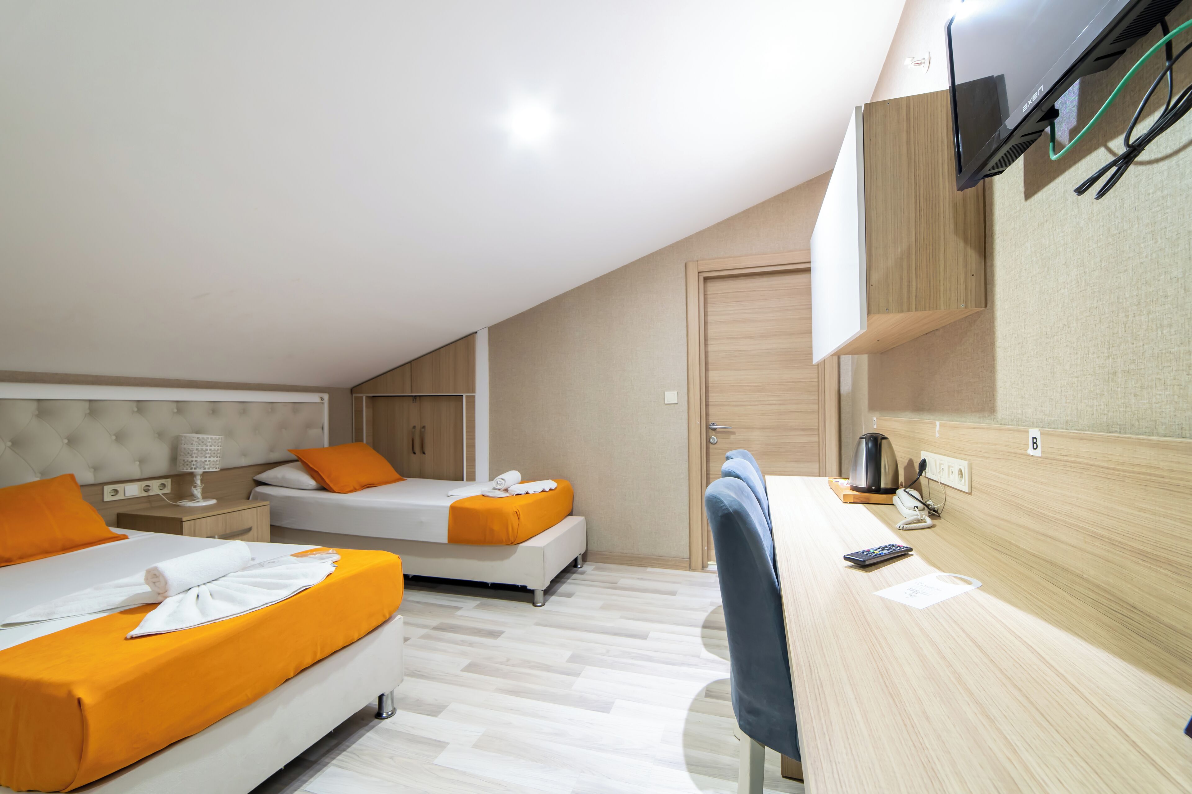 Une chambre d’hôtel moderne équipée de deux lits, d’un bureau, d’une chaise, d’une télévision et d’une machine à café.
