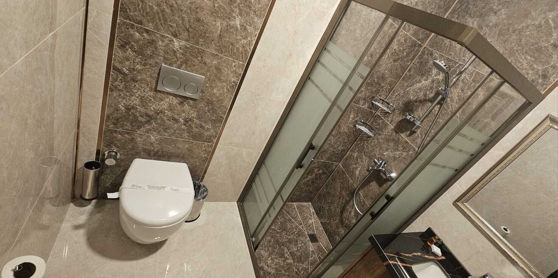 A modern bathroom with a toilet, shower, and glass-enclosed shower area.