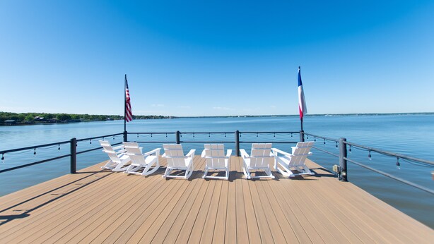 Een houten terras met witte lounge stoelen en twee Amerikaanse vlaggen.
