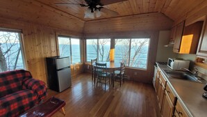 A cozy cabin with a wooden interior, a dining area with a table and chairs, a refrigerator, a microwave, and a sink. - Superior Reflections  Cabin #2 on Lake Superior (Schroeder)