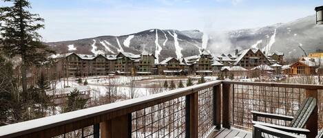 A resort with multiple buildings, a snowy landscape, and a wooden deck with benches.