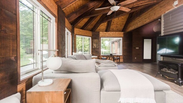 A spacious living room with a large sectional sofa, a wooden ceiling, and a television.