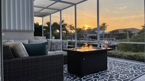 Un patio exterior con una chimenea, asientos y vistas a la puesta de sol.