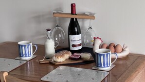 Ett träbord med en vinflaska, glas, ägg, en liten figurin av en tupp och två kaffemuggar.