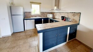 A compact kitchen with a refrigerator, dishwasher, microwave, and a coffee maker. - Beautiful apartment in Residence with swimming pool, garden and terrace (Sainte-Lucie de Porto-Vecchio)