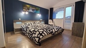 A bedroom with a bed, bedside tables, a chair, a window with blinds, and a painting on the wall. - Fabulous holiday home with sea view for the whole family! (Balchik)