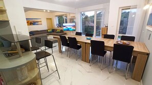 A modern dining area with a wooden table, black chairs, and a TV mounted on the wall.