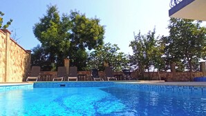 A swimming pool with clear blue water, surrounded by stone walls and trees. - Fabulous holiday home with sea view for the whole family! (Balchik)