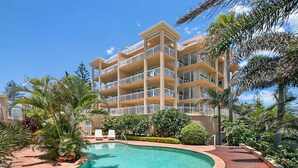 A multi-story hotel with a swimming pool surrounded by tropical plants. - Orion 6 - Beachfront Rainbow Bay - All Linen Supplied - Min. 3 Night Stays! (Rainbow Bay)