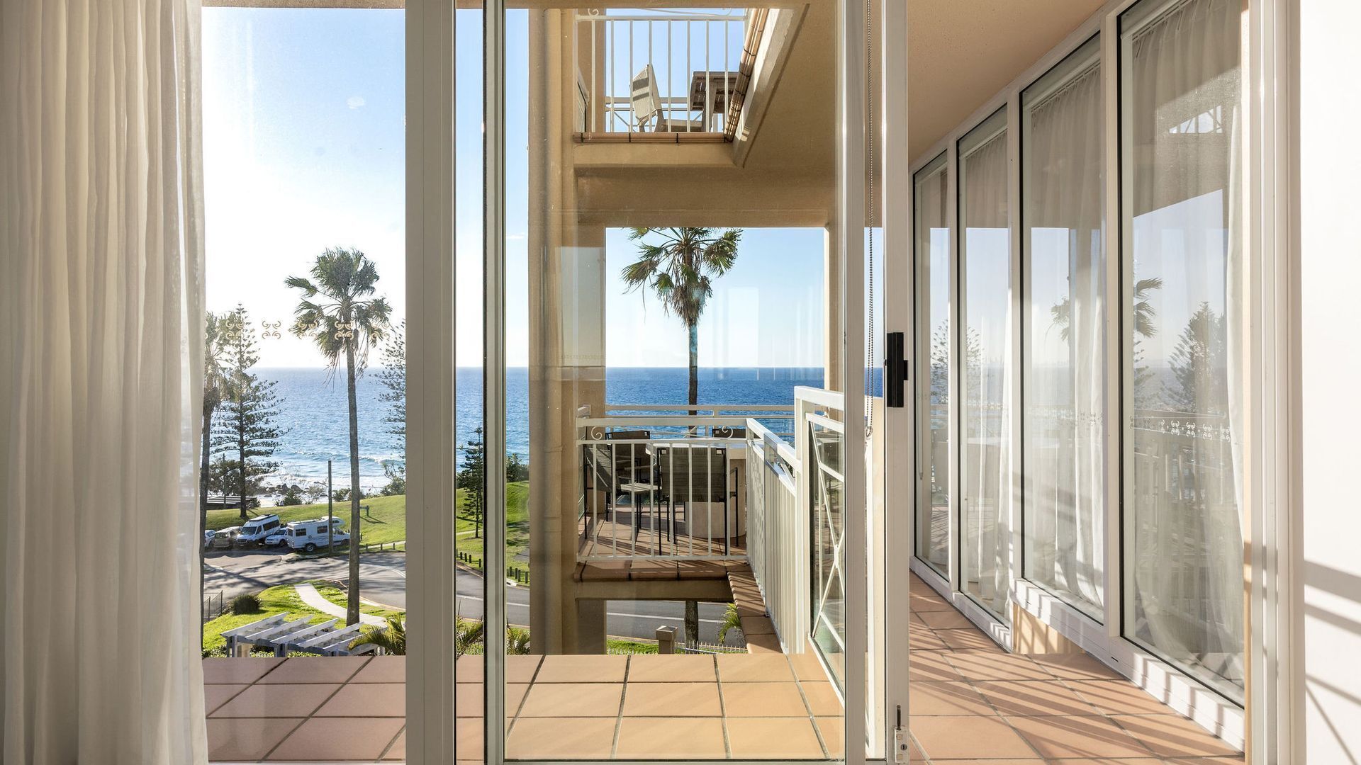 Un balcon avec vue sur la mer et les palmiers.