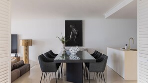 A modern dining area with a central table, chairs, a decorative vase, and a wall-mounted artwork.