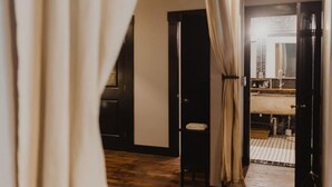 Une pièce comprenant un lit, une petite table et une salle de bain visible à travers une porte ouverte.