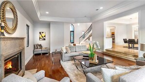 A spacious living room with a fireplace, grey sofas, a coffee table, and a staircase leading to another level. - The Light of Mount Olympus (Los Angeles)