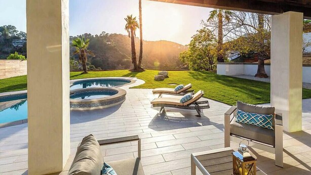 A poolside area with a hot tub, lounge chairs, and a view of a mountainous landscape. - The Light of Mount Olympus (Los Angeles)