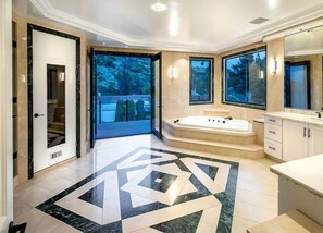 Ein modernes Badezimmer mit einer großen Badewanne, einer separaten Duschkabine und einem Waschtisch mit Spiegel.