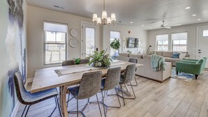 Amplia sala de estar con una mesa de comedor de madera, sillas acolchadas, un sofá y un sillón verde.